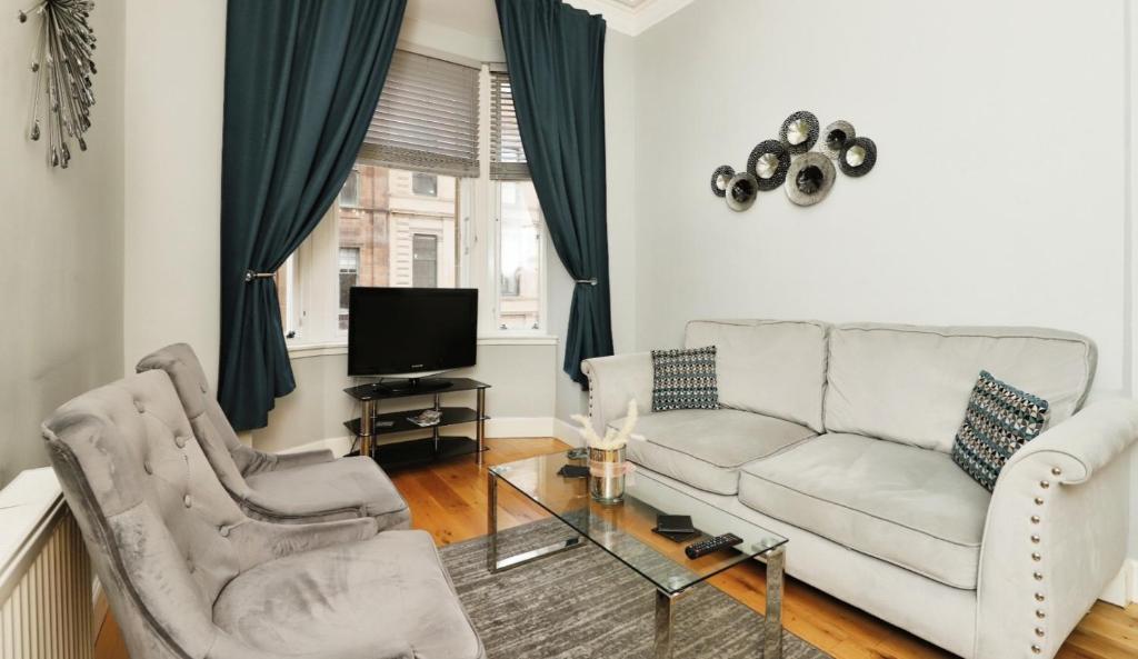 a living room with a couch and two chairs and a tv at Modern Glasgow City Centre Apartment in Glasgow