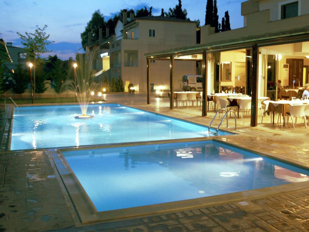 a swimming pool with a fountain in front of a house at Zeis Edo Luxury Apartments in Tolo