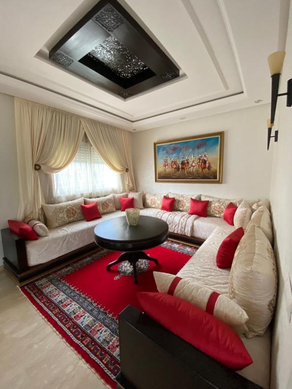 ein Wohnzimmer mit einem Sofa und roten Kissen in der Unterkunft Villa de luxe centrale Harhoura in El Harhoura