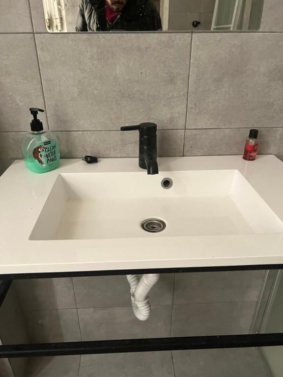 un lavandino bianco in un bagno con una persona in uno specchio di bken Aprt ad Anversa