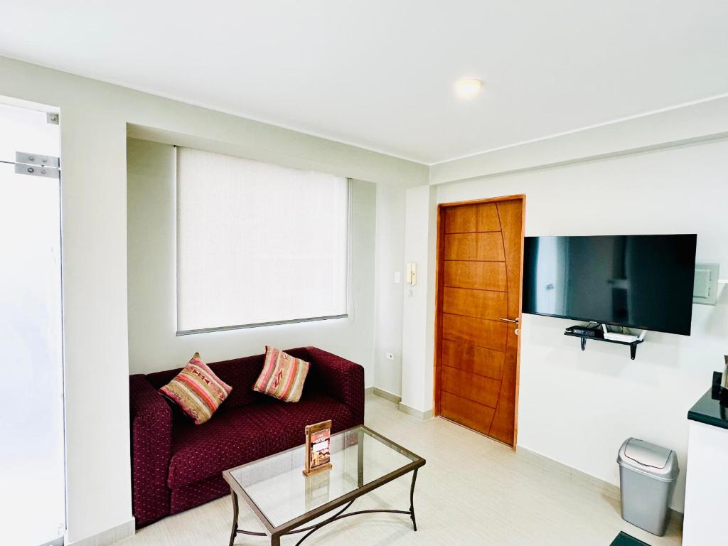 a living room with a red couch and a tv at Las Viñas - Departamentos Privados in Ica