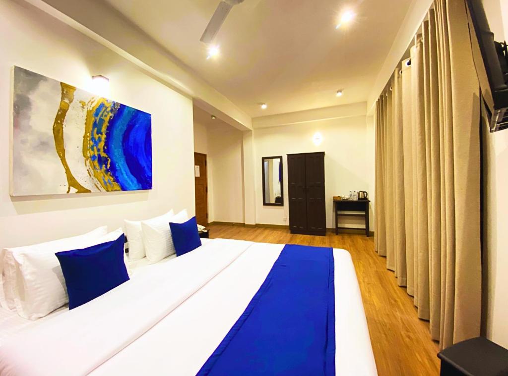 a bedroom with a large bed with blue and white pillows at Queens Mount Glen Heights in Nuwara Eliya