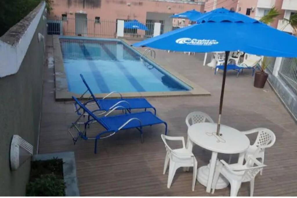 a swimming pool with a table and an umbrella at Apartamento aconchegante in Ilhéus