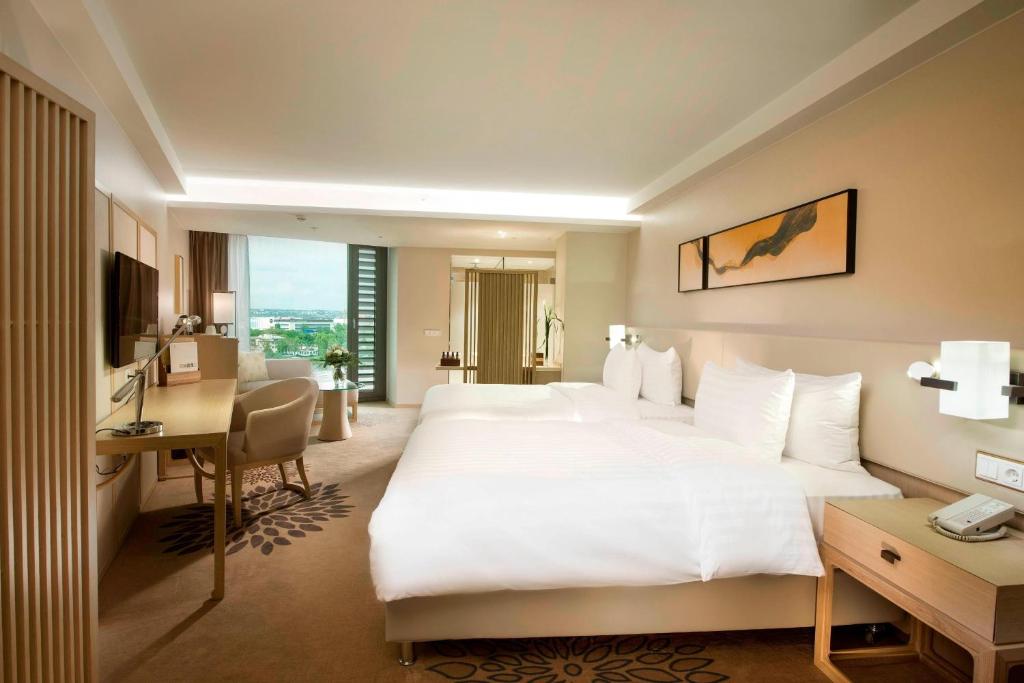 a hotel room with a large white bed and a desk at Delta Hotels by Marriott Frankfurt Offenbach in Offenbach