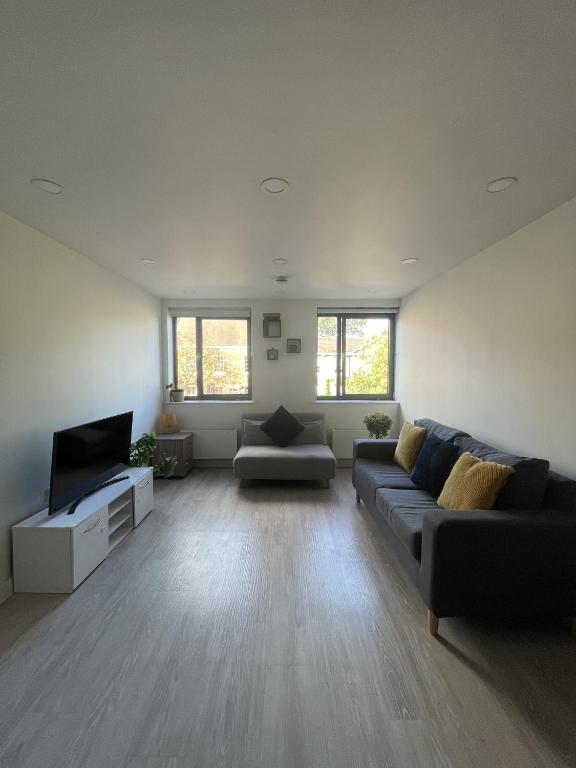 uma sala de estar com um sofá e uma televisão de ecrã plano em Large Suite - Bedford City Centre em Bedford