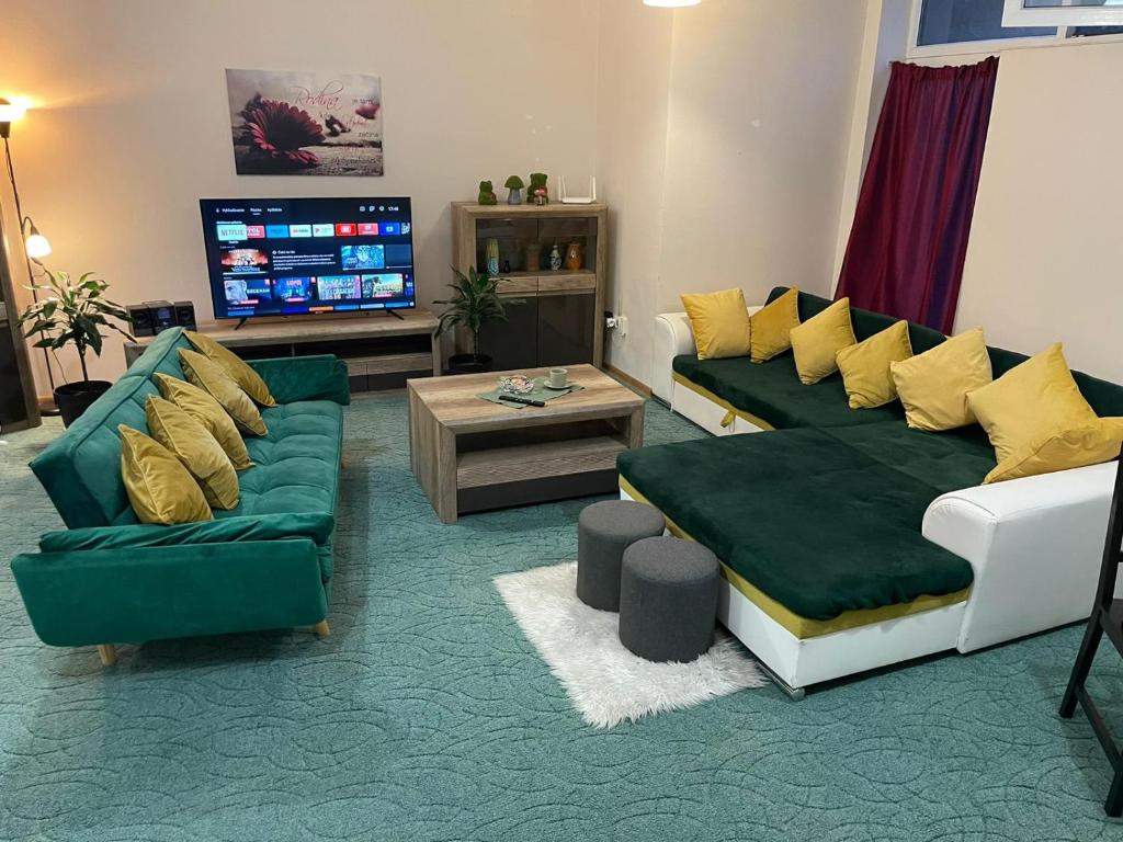 a living room with green couches and a tv at Veľký apartman in Karlova Ves