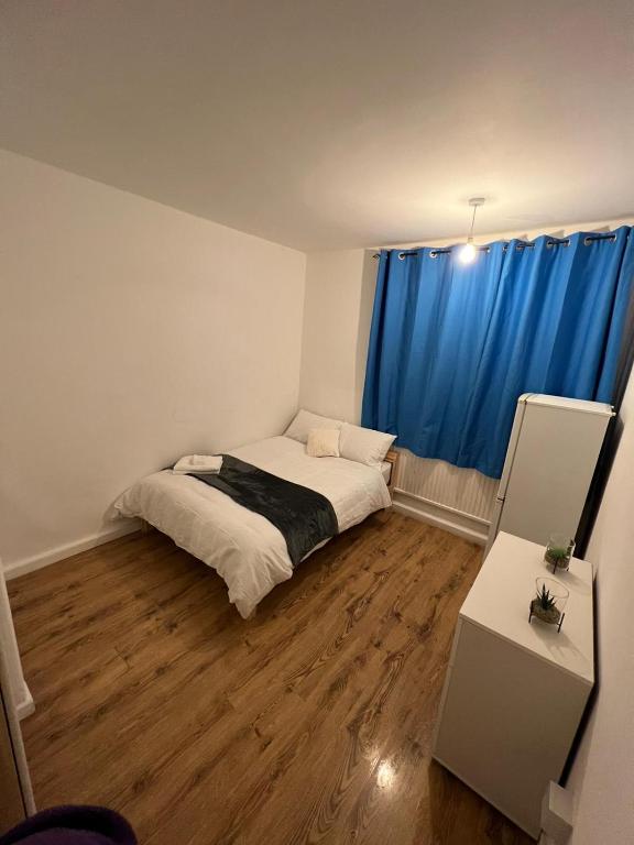 a bedroom with a bed and a blue curtain at Nice Battersea Flat in London