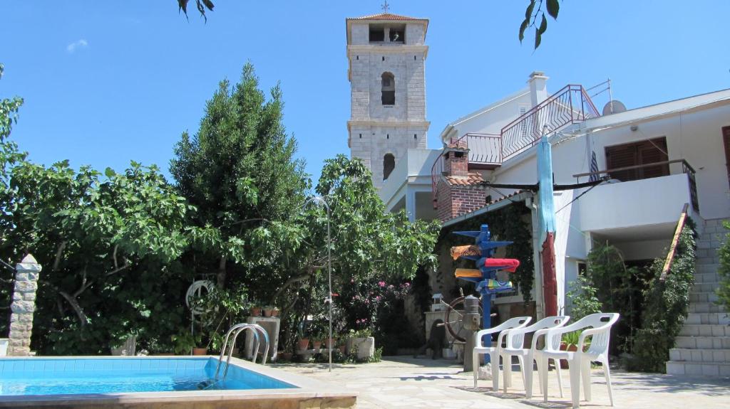 een persoon die naast een zwembad met een klokkentoren staat bij Dvor Maraca bell tower apartments in Tisno