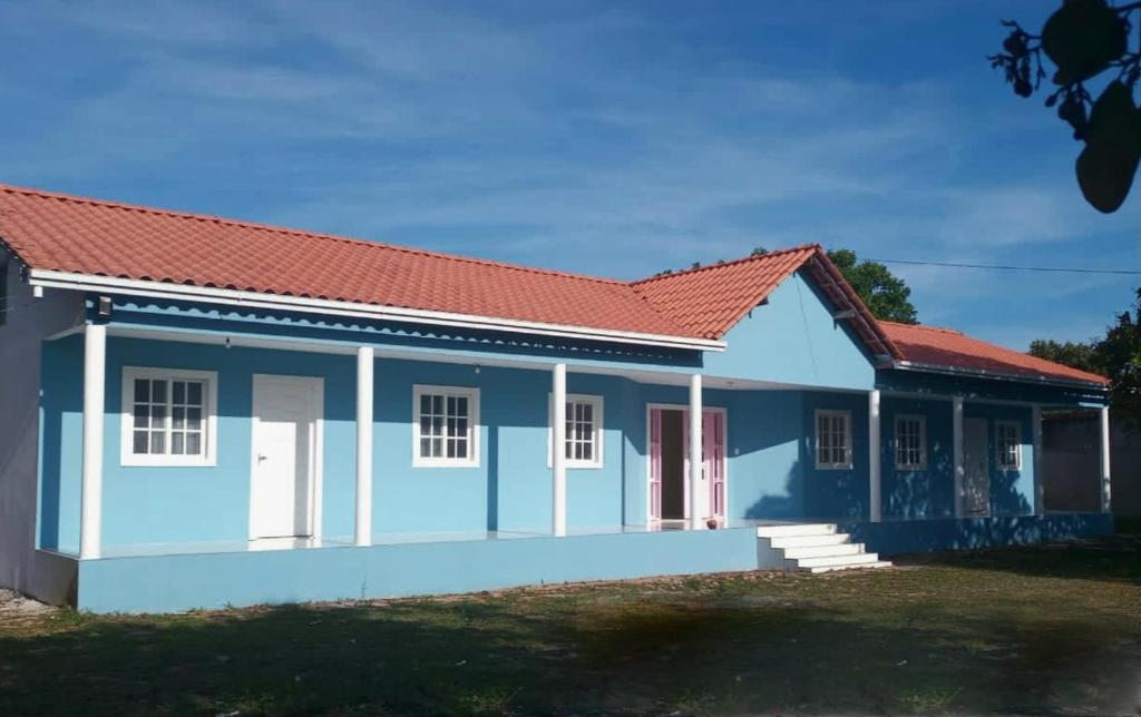 une maison bleue et blanche avec un toit rouge dans l'établissement Pousada Raio de Sol - Ilha de Itaparica- Catu á 150 m da praia, à Vera Cruz de Itaparica
