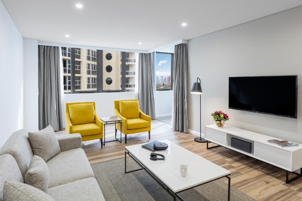 a living room with a couch and two yellow chairs at Meriton Suites Bondi Junction in Sydney