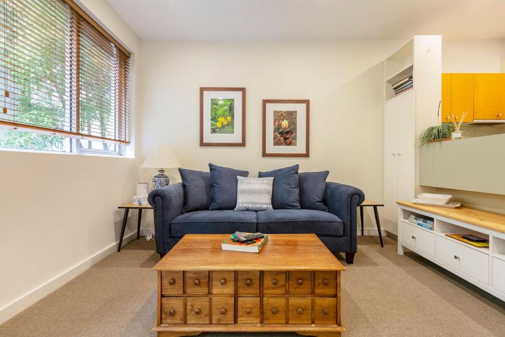uma sala de estar com um sofá azul e uma mesa de centro em Experience the St Kilda Vibe from a Cosy Retreat em Melbourne