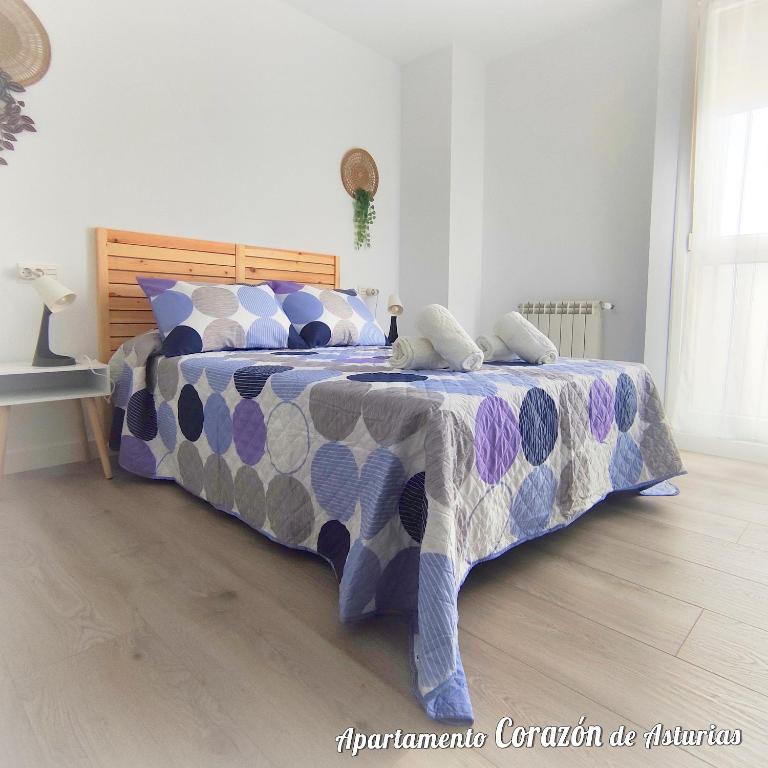a bedroom with a bed with a blue and purple comforter at CORAZÓN DE ASTURIAS in Piedras Blancas