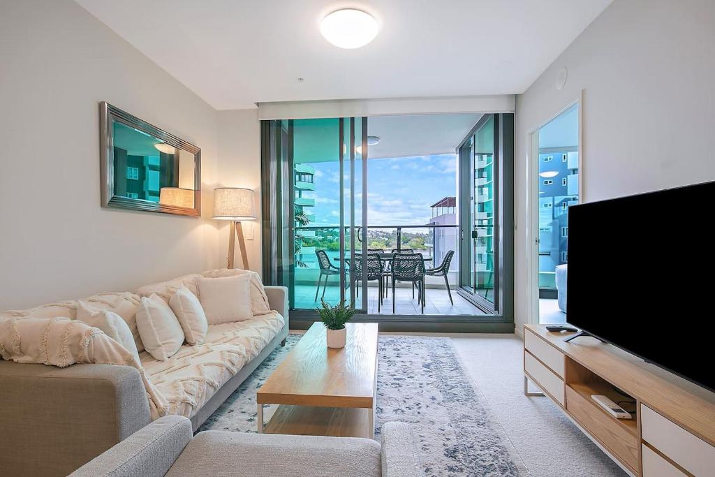 a living room with a couch and a flat screen tv at 'Riverfront Flow' Poolside and Portside in Hamilton in Brisbane