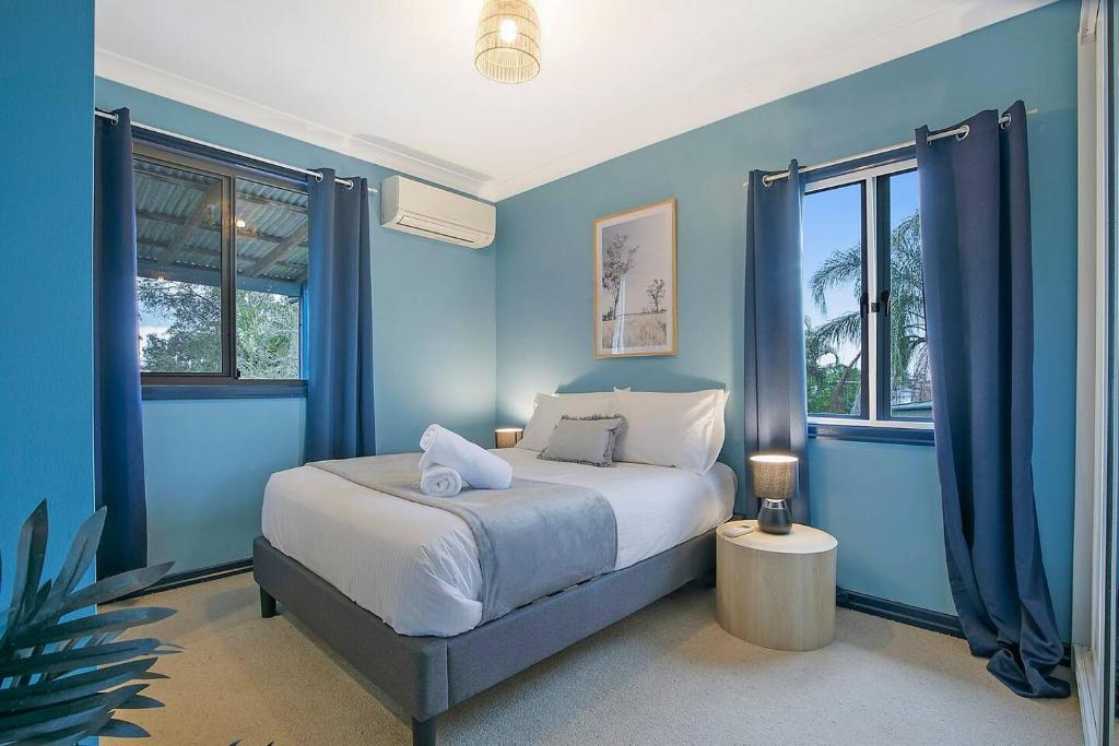 um quarto azul com uma cama e 2 janelas em 'Eucalypt Cottage' A Tranquil Family Hideaway em Brisbane