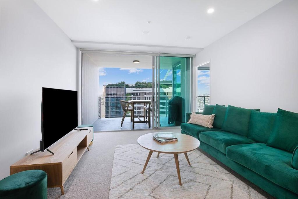 - un salon avec un canapé vert et une table dans l'établissement The Skyring - Effortless Resort-style Living, à Brisbane