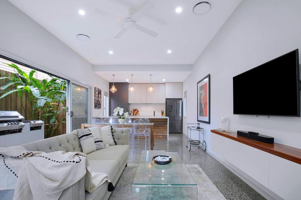 een woonkamer met een bank en een tv aan de muur bij Nundah's Lush Haven - Serene Family Townhouse Escape in Brisbane
