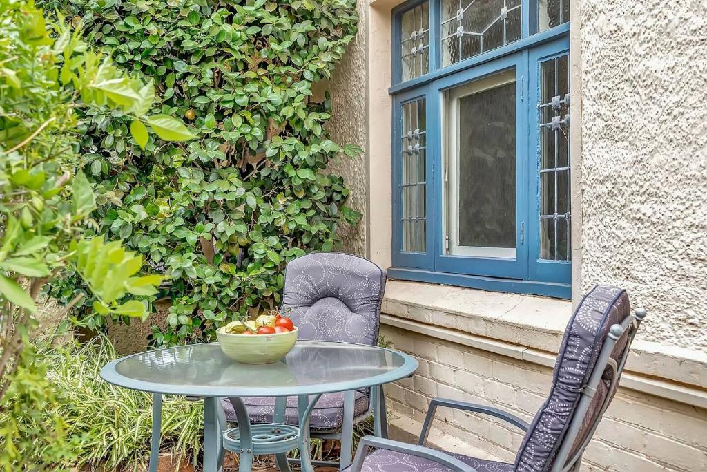 ein Tisch und Stühle auf einer Terrasse mit einer Obstschale in der Unterkunft 'The Nook' Peaceful Toorak Gardens Retro Cottage in Adelaide