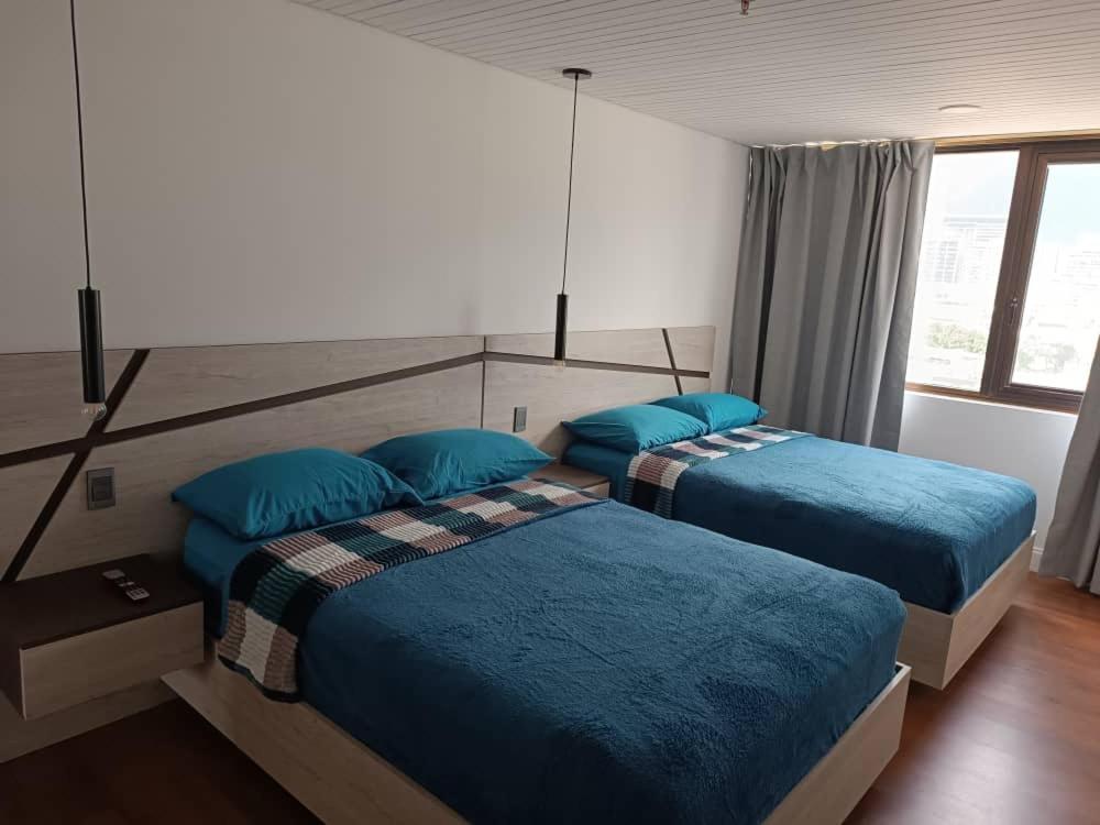 2 camas en un dormitorio con almohadas azules en Apartahotel, en Caracas