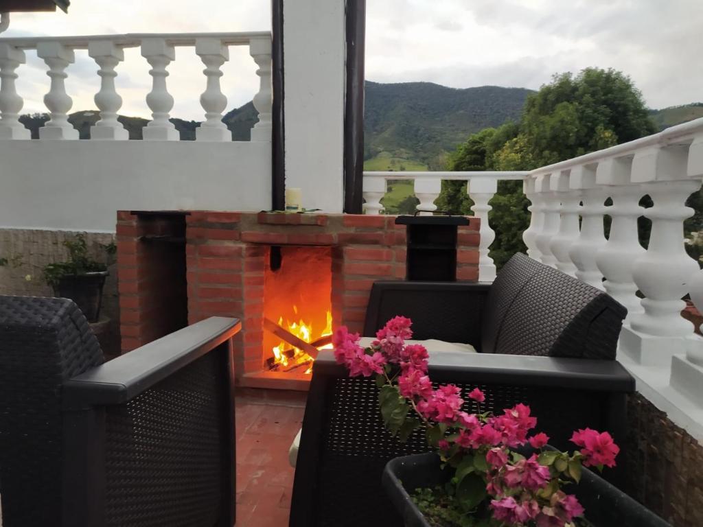 una chimenea en un balcón con sillas y flores en Cozy 2-BR Apt with mountain view, en Medellín