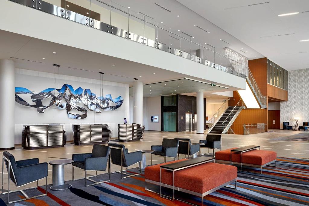 a lobby with chairs and tables and a staircase at Calgary Airport Marriott In-Terminal Hotel in Calgary