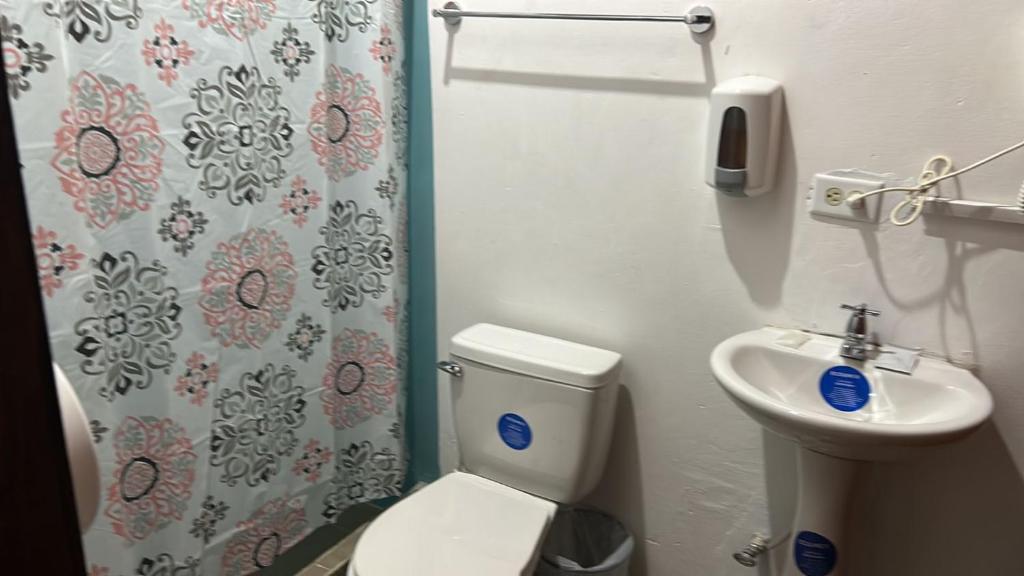 a bathroom with a toilet and a sink and a shower curtain at SEVEN DAYS HOTEL B&B in San Pedro Sula