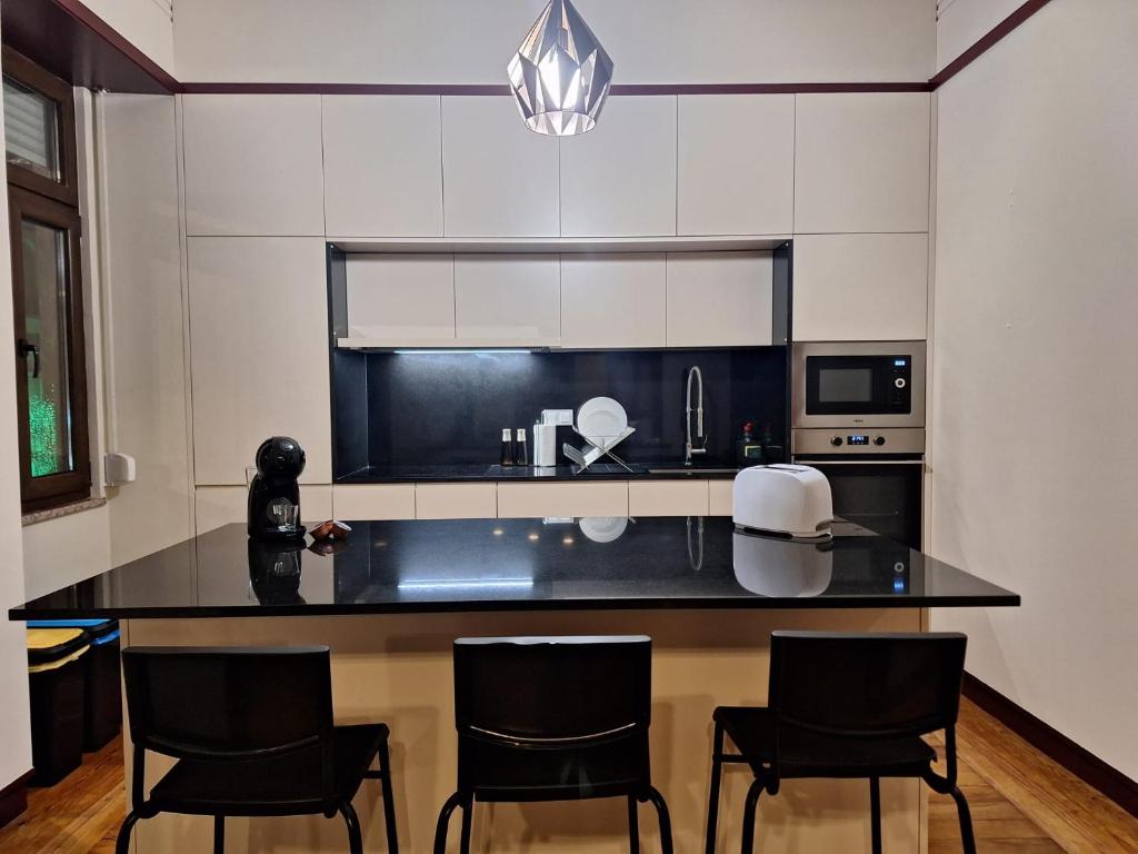 a kitchen with a black counter top and black chairs at Easy Host Porto in Porto
