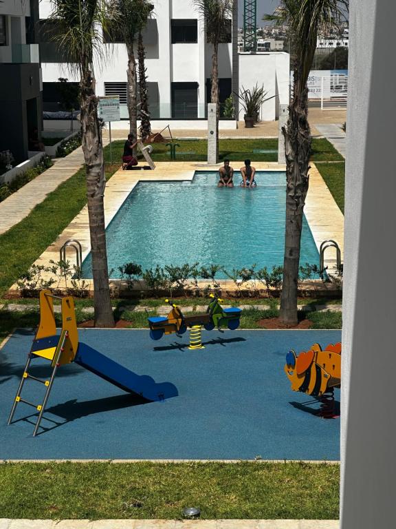 uma piscina com parque infantil com pessoas a brincar nela em Belle appartement à découvrir em El Harhoura