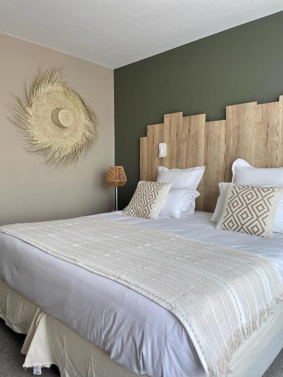 a bedroom with a large bed with white sheets and pillows at Hôtel Restaurant BO &amp; MIA in La Baule