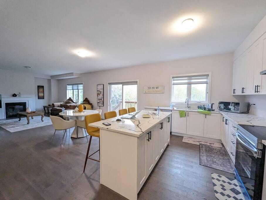 a kitchen with white cabinets and a living room at Stylish 5-Bedroom Retreat Near Port Dover and Turkey Point Beach in Simcoe