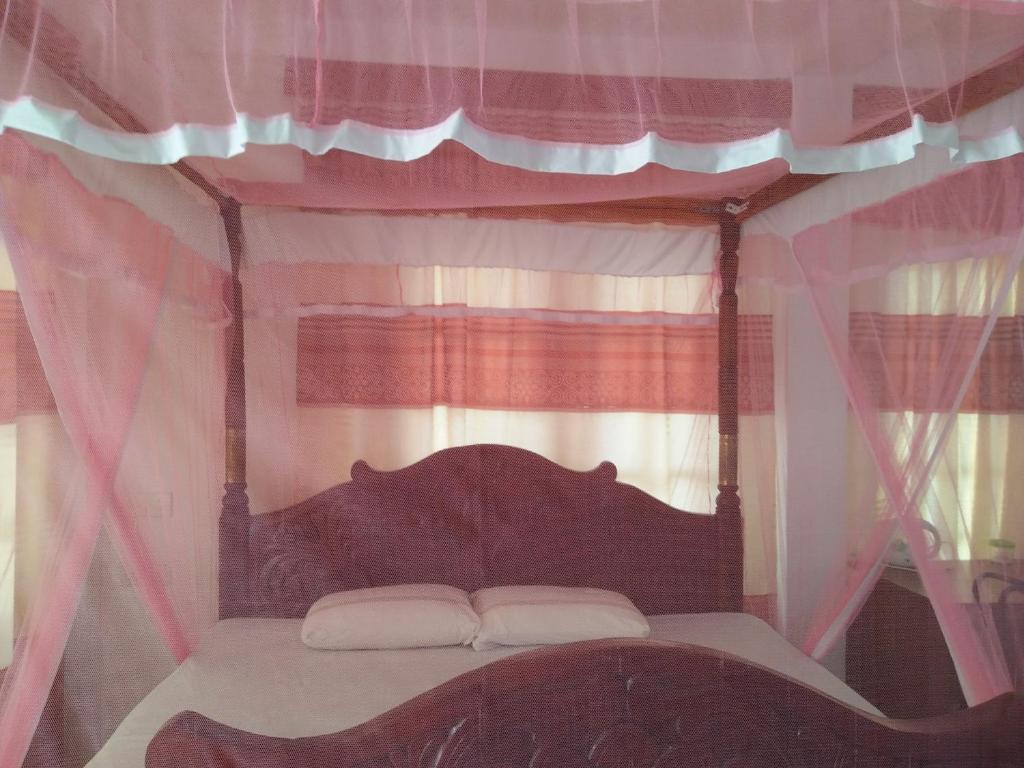 キャンディにあるOld Town Hotelのベッドルーム(ピンクのカーテン付きの天蓋付きベッド1台付)