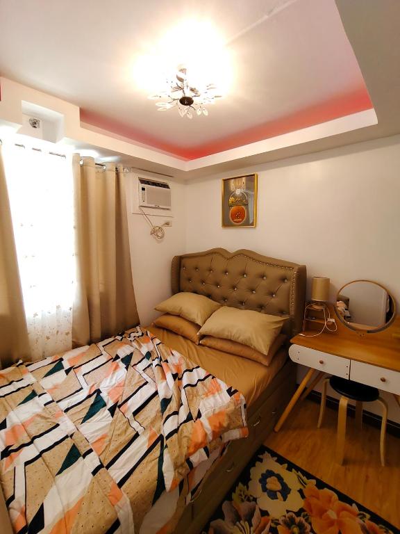 a bedroom with a bed and a couch and a table at Rj condotel @arezzo place davao in Davao City