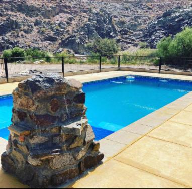 uma piscina com uma parede de pedra ao lado de uma montanha em Cabañas Altura de Varillar em Varillar