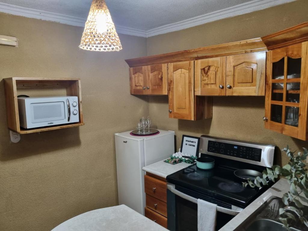 cocina con nevera blanca y microondas en apartamento equipado en Amatitlán