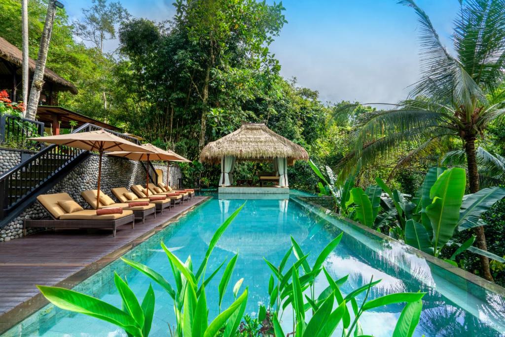a swimming pool in a resort with chairs and a gazebo at The Hidden Palace by Hanging Gardens in Payangan