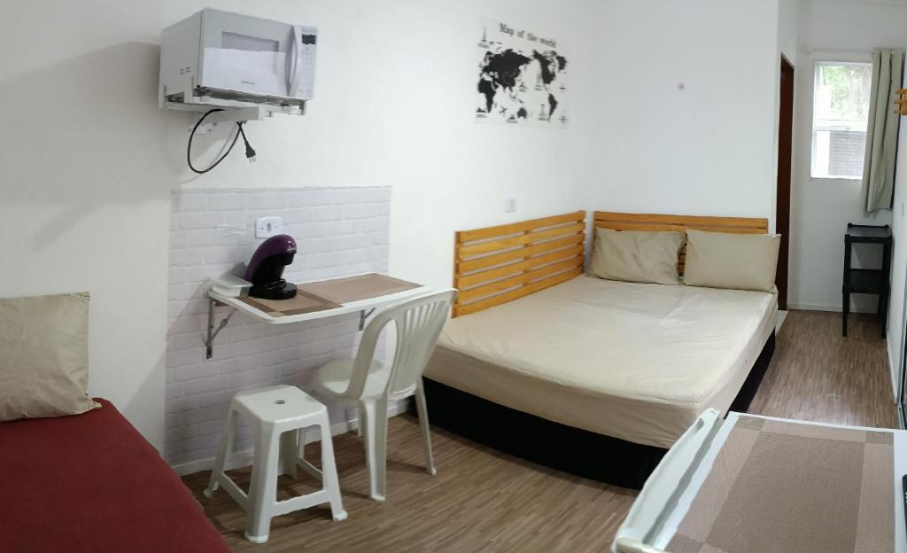mały pokój z łóżkiem i małym stołem w obiekcie Suíte Independente - Praia Indaiá e Riviera - MarDoceLar Bertioga w mieście Bertioga