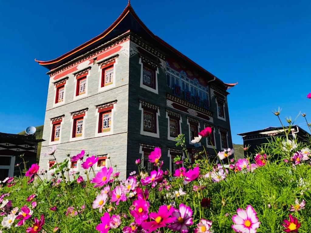 un edificio con fiori rosa di fronte di Zhuji Inn a Xinduqiao