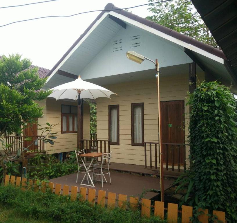 ein kleines weißes Haus mit einem Tisch und einem Sonnenschirm in der Unterkunft Bansuan Inthanon Resort in Chom Thong