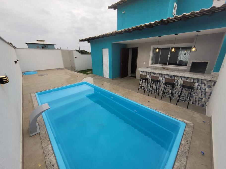 a large blue swimming pool in front of a house at Casa de Praia - Búzios in Búzios