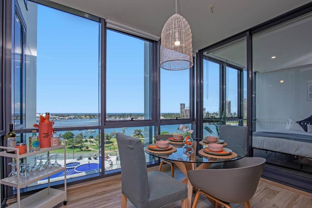 a dining room with a table and chairs and windows at Como Prestige Breathtaking Southport Sundale in Gold Coast