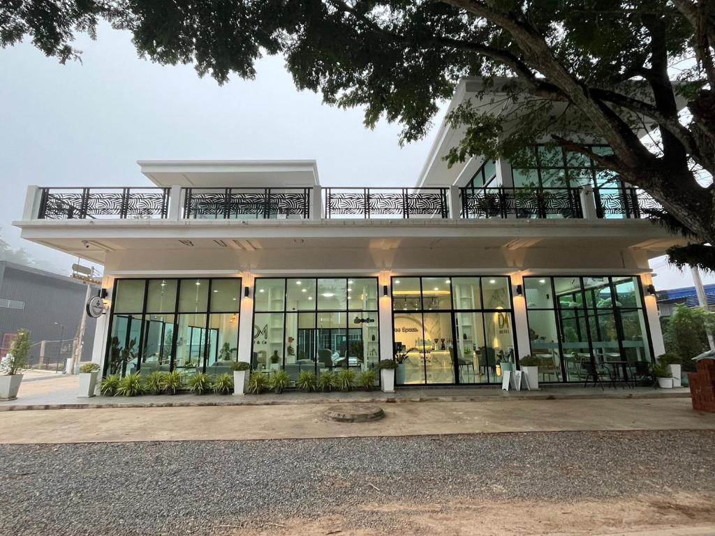 DM Hotel & Cafe في Ban Na Tho: مبنى مكتب شبابيكه كبيره وبلكونه