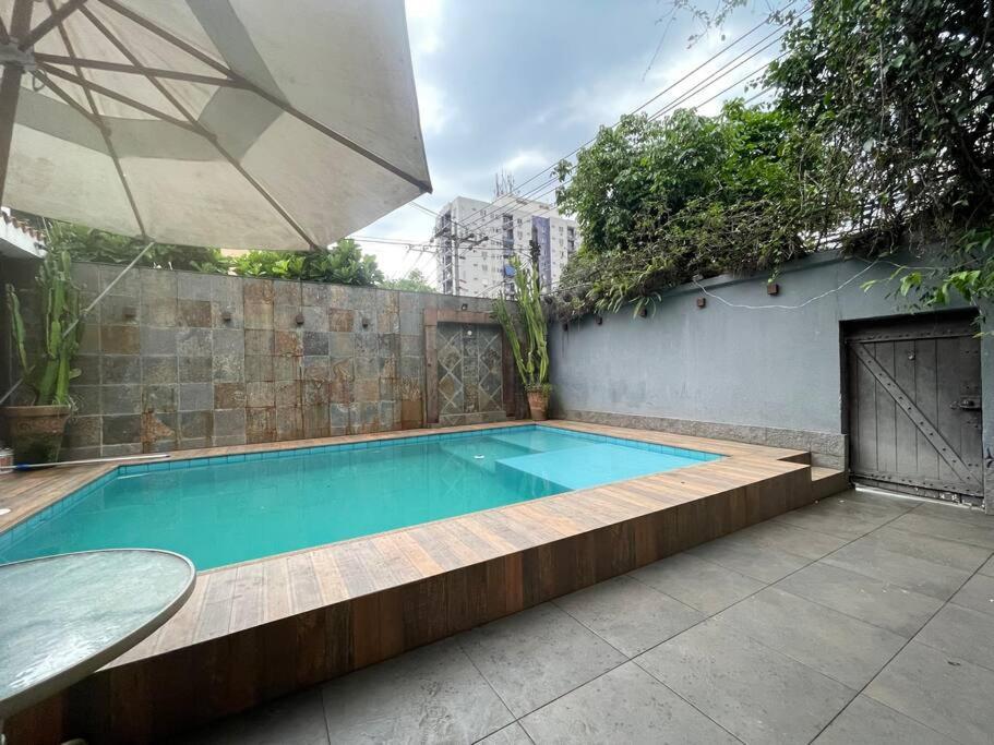 a swimming pool with a table and an umbrella at Casa em Freguesia (Jacarepaguá) in Rio de Janeiro