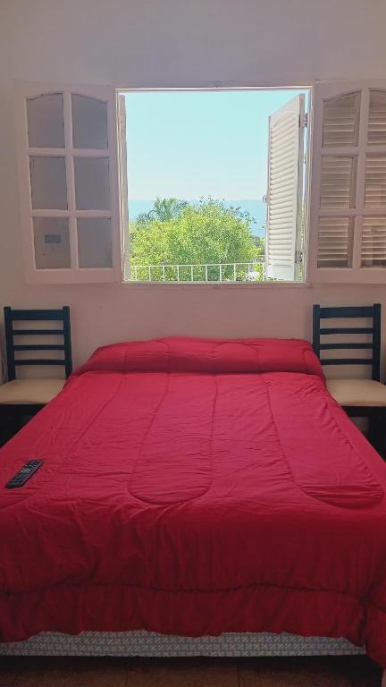 een rood bed in een slaapkamer met een raam bij Alquiler temporario Catamarca in San Fernando del Valle de Catamarca