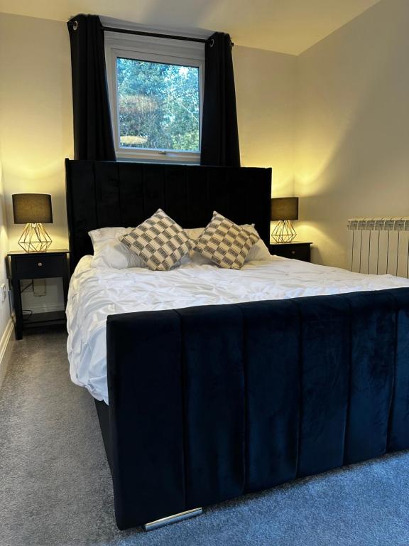 a large bed with a black headboard and a window at Entire Apartment boutique king size bed near Town Centre in Colchester
