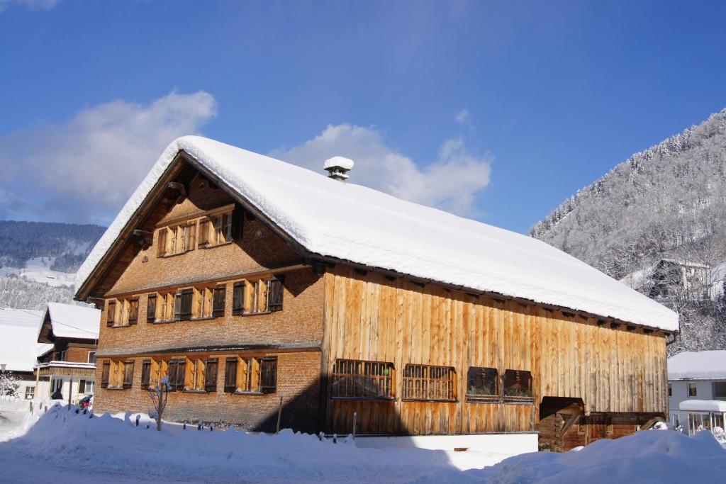 ein großes, schneebedecktes Holzgebäude in der Unterkunft Naze`s Hus Mellau in Mellau