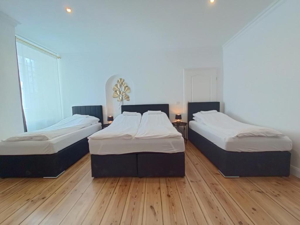 3 camas en una habitación con suelo de madera en central 2Room Apartment XBerg en Berlín