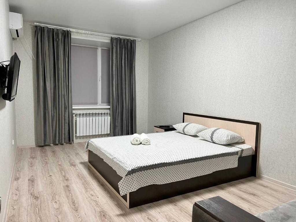 um quarto com uma cama e uma grande janela em Уютная и новая квартира в Костанае em Qostanay