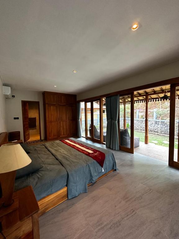 um quarto com uma cama grande num quarto com janelas em Gamelan Amed Villa em Amed