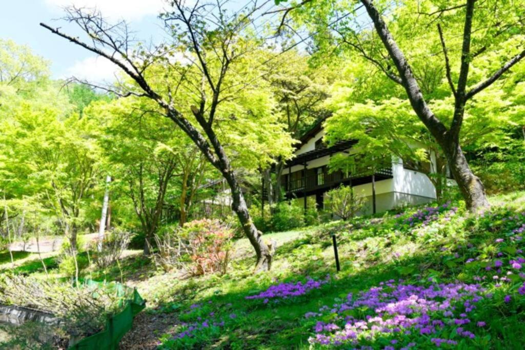 a garden with purple flowers in front of a building at 四季の彩りが鮮やかなレイクビューハウス 軽井沢駅から車で10分 in Karuizawa