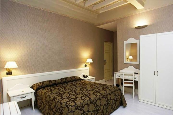ヴィテルボにあるパラッツォ リアリオのベッド1台とテーブル2台が備わるホテルルームです。