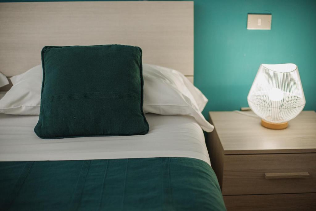 een bed met een groen kussen en een lamp op een nachtkastje bij Maison Escaliers in Aosta